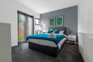 a bedroom with a large bed with a blue blanket at Tranquil Six Bedroom Haven in Northampton