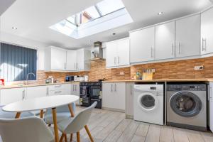 a kitchen with white cabinets and a table and chairs at Tranquil Six Bedroom Haven in Northampton