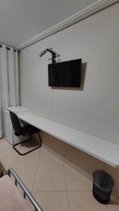 białe biurko z czarnym monitorem na ścianie w obiekcie Quarto com 2 Camas de Solteiro Ar Condicionado Frigobar Smart TV e Café da Manhã w mieście Porto Alegre