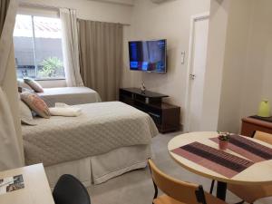 a hotel room with two beds and a table and a tv at Studio Bena 2 - single bed - próx Shopping Iguatemi in Campinas