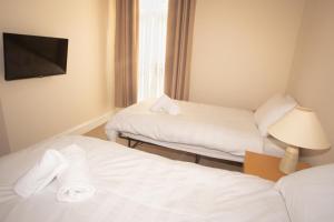 a hotel room with two beds and a flat screen tv at Norton Serviced Apartments in Stockton-on-Tees
