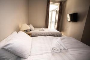 two beds in a room with white sheets and a window at Norton Serviced Apartments in Stockton-on-Tees