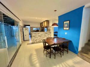 a dining room with a wooden table and a blue wall at Casa Frente Praia Búzios in Búzios