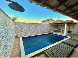 a swimming pool in front of a brick wall at Casa Frente Praia Búzios in Búzios