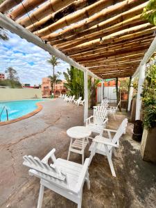 un patio con sillas blancas, una mesa y una piscina en ARASARÍ Hotel Iguazú en Puerto Iguazú