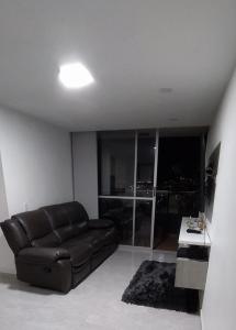 uma sala de estar com um sofá de couro preto e uma mesa em Hermoso apartamento en sector exclusivo. em Bello