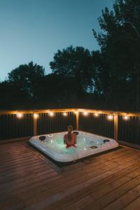 a woman in a hot tub on a deck at night at Andas cabin CITQ#313550 in Lac-Superieur
