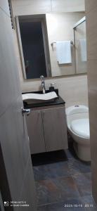 uma casa de banho com um lavatório, um WC e um espelho. em Hermoso apartamento en sector exclusivo. em Bello