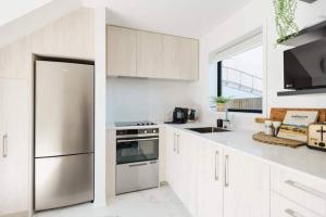 a kitchen with white cabinets and a stainless steel refrigerator at CBD with Style and Luxury - Free Parking in Christchurch