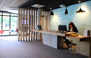 une femme assise sur un bureau avec un ordinateur dans l'établissement ibis Lille Centre Grand Palais, à Lille