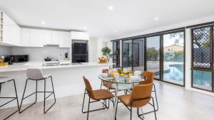 Una cocina y un comedor con una mesa de cristal y sillas. en Coastal Breezes, en Corlette