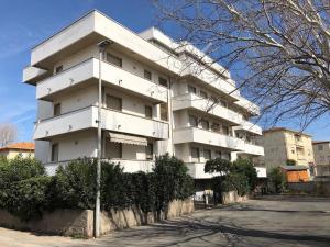 un edificio blanco con arbustos delante de él en Mar-Vada Apartment Relax at the Tuscany coast, en Vada