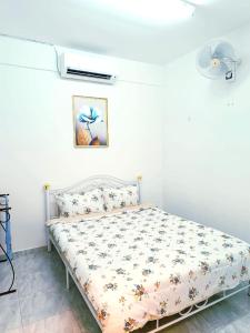 a bed in a room with a white wall at D'Luna Homestay Terengganu - LADANG GEMILANG 2 in Kuala Terengganu