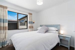 a white bedroom with a bed and a window at Wander into Wanaka in Wanaka