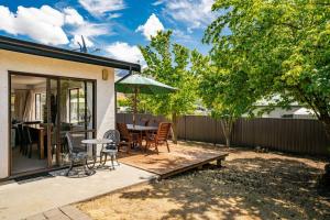 a patio with a table and chairs and an umbrella at Wander into Wanaka in Wanaka