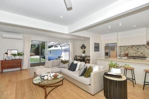 a living room with a white couch and a kitchen at Coastal Escape in Long Jetty