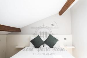 a bedroom with a white bed with green pillows at Casa Porta Nova AL in Guimarães