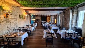 un restaurante con mesas y sillas blancas y una pared de piedra en La Truite de la Loue, en Quingey