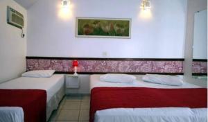 a bedroom with two beds with red and white sheets at Villa dos anjos in Olímpia