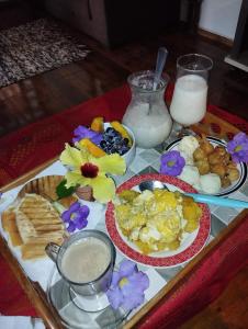 a tray of breakfast foods on a table with milk at Recanto do paraiso in Itacaré