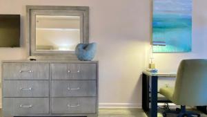 a dresser with a mirror and a desk with a chair at Royal Inn Hotel in Royal Palm Beach