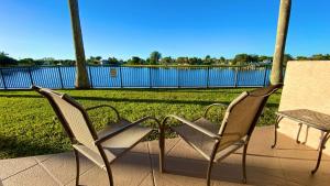 dwa krzesła i stół na patio z jeziorem w obiekcie Royal Inn Hotel w mieście Royal Palm Beach