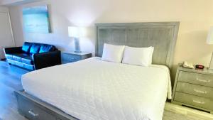 a bedroom with a large white bed and a chair at Royal Inn Hotel in Royal Palm Beach