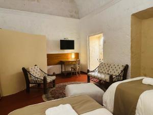 a bedroom with two beds and a desk with a television at Hotel Piru Wasi in Arequipa