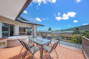 a patio with a table and chairs on a balcony at Spa Haven 17A in Airlie Beach