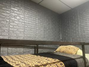 1 dormitorio con cama y pared de ladrillo en La casa de la 12 en Campeche