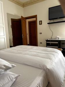 a bedroom with two beds and a television on the wall at The Glasshouse Pools in Cairo