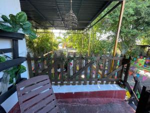 un banco de madera sentado en un porche con una valla en La casa de la 12 en Campeche
