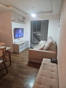a living room with a couch and a flat screen tv at Apartamento 2 quartos com 1 suite in Serra