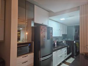 a kitchen with a stainless steel refrigerator and white cabinets at Apartamento 2 quartos com 1 suite in Serra