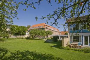 a house with a green lawn in front of a building at Emmaus Hostel in Haslev