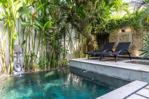 a pool with two chairs and a table next to a building at Villa Cantik in Canggu