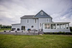 ein großes weißes Haus mit einer großen Veranda und einem Hof in der Unterkunft Lakeside Vineyard Farmhouse in North East