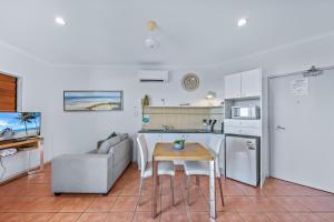 uma cozinha e sala de estar com um sofá e uma mesa em Spa Haven 17B Ocean View em Airlie Beach
