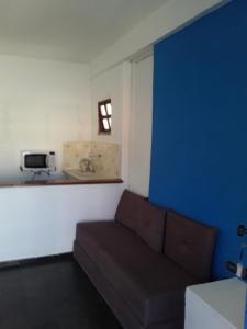 a living room with a couch and a blue wall at Santorini Flats in Arraial do Cabo