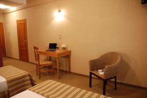 um quarto de hotel com uma secretária com um computador portátil e uma cadeira em CATANGE HOTEL em Charata