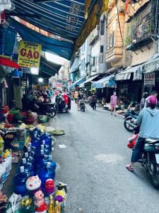 a street with a market with people on motor bikes and people in an alley at Lanha Hotel - Homestay in Hanoi