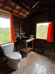 uma casa de banho com um WC, um lavatório e 2 janelas em Boong House em Bao Loc