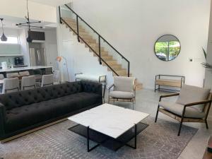 uma sala de estar com um sofá preto e cadeiras em Stunning Modern Home w Pool & Hot Tub in DT Austin em Austin