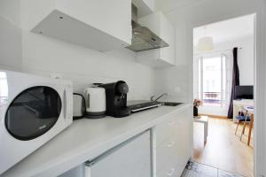 uma cozinha branca com um micro-ondas no balcão em Charming and Cosy studio Levallois em Levallois-Perret
