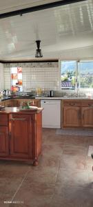 a large kitchen with wooden cabinets and a large window at Maison de charme, en Plaine Poésie -chez l'habitant- in La Plaine des Palmistes