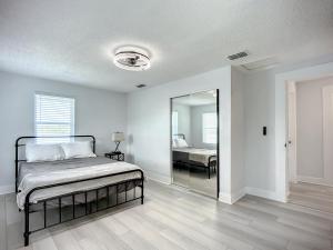 a white bedroom with a bed and a mirror at Trout River Oasis in Jacksonville