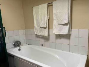 Lindy's Guesthouse في ماسيرو: حوض استحمام أبيض في الحمام مع المناشف