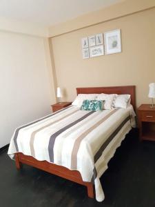 ein Schlafzimmer mit einem Bett mit einer gestreiften Decke in der Unterkunft Acogedor Departamento en la Playa in Punta Hermosa
