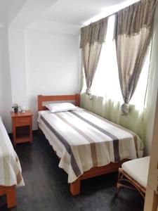 ein Schlafzimmer mit einem Bett mit einer gestreiften Decke und einem Fenster in der Unterkunft Acogedor Departamento en la Playa in Punta Hermosa
