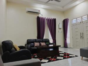 a living room with black leather furniture and purple curtains at SERI IBAI DAMAI in Kuala Terengganu
